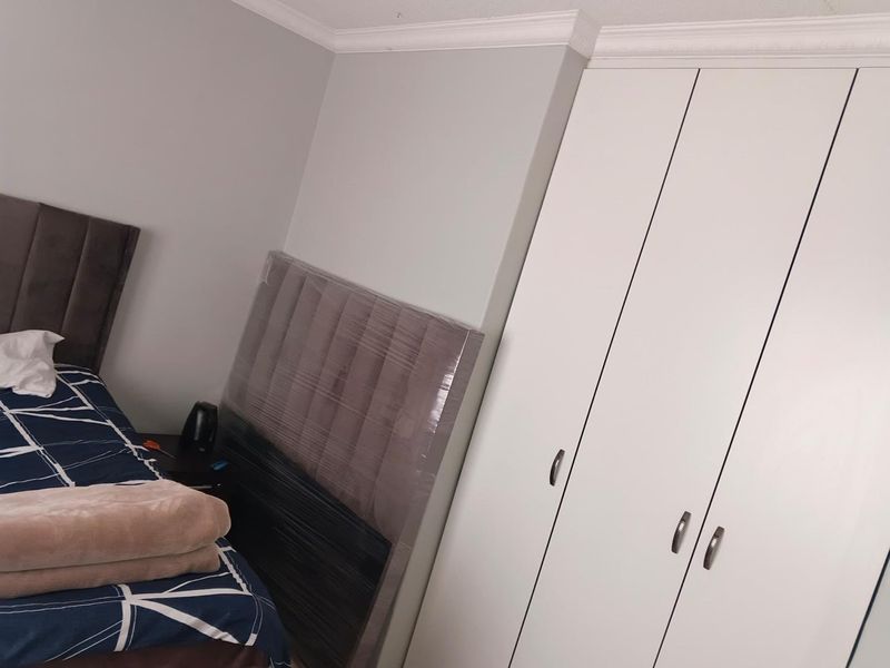 A bedroom featuring a white built-in wardrobe with modern handles and decorative ceiling cornicing.