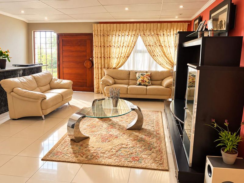 A spacious living room featuring polished tiled flooring, recessed ceiling lighting, and a solid timber entrance door with an integrated security gate.