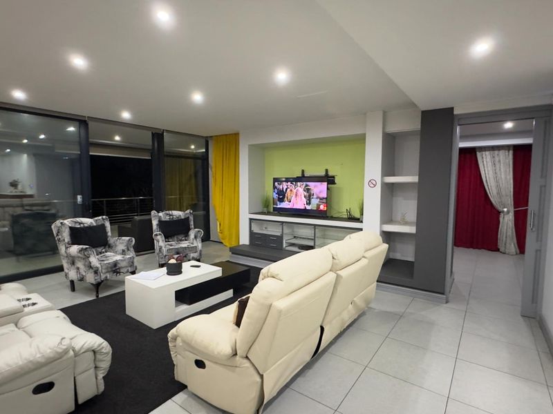 Spacious living room featuring large sliding glass doors, recessed ceiling lighting, and a built-in media unit with integrated shelving.