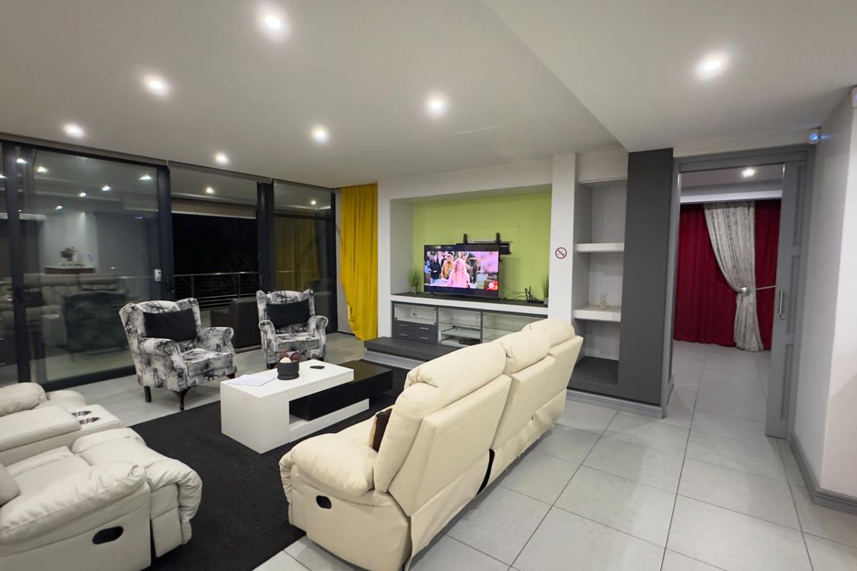 Spacious living room featuring large sliding glass doors, recessed ceiling lighting, and a built-in media unit with integrated shelving.