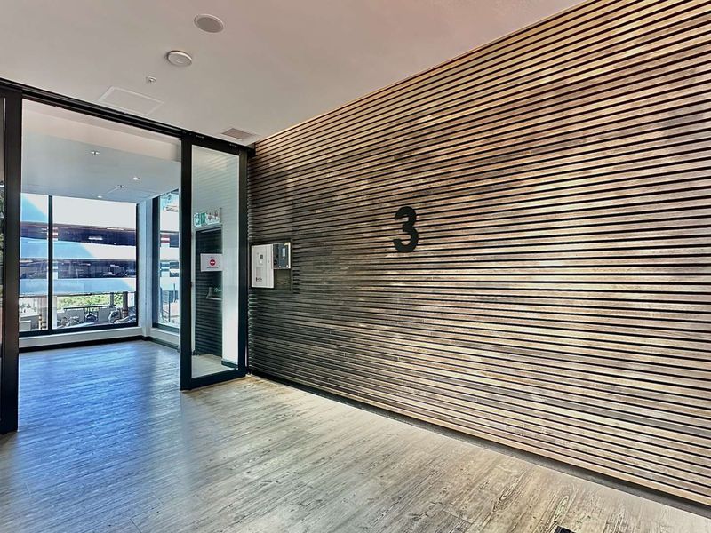 Modern office entrance lobby featuring a striking timber slat feature wall, glass partitioning, and high-quality wood-look flooring.