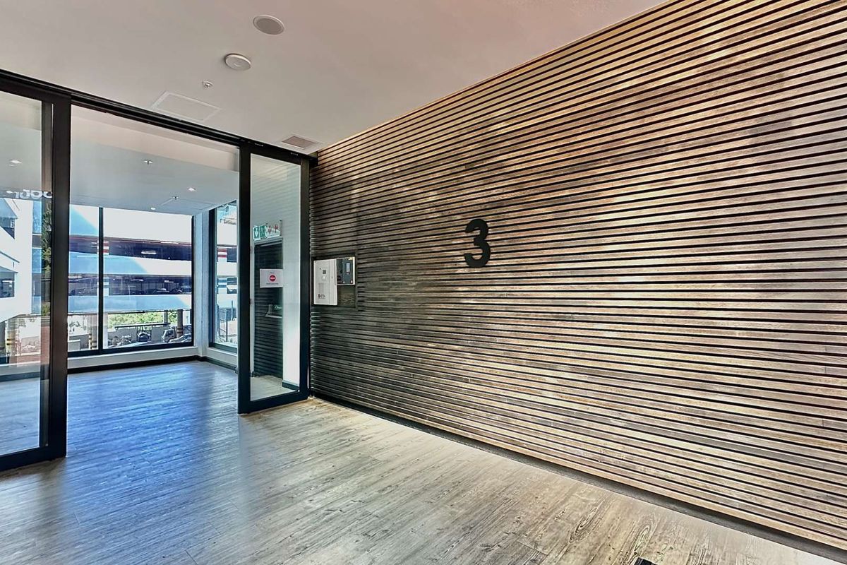 Modern office entrance lobby featuring a striking timber slat feature wall, glass partitioning, and high-quality wood-look flooring.