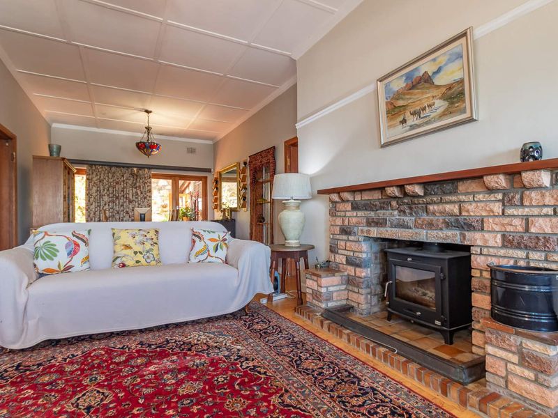 A cozy living room featuring a prominent brick fireplace with a built-in wood-burning stove, timber flooring, and a classic tiled ceiling.