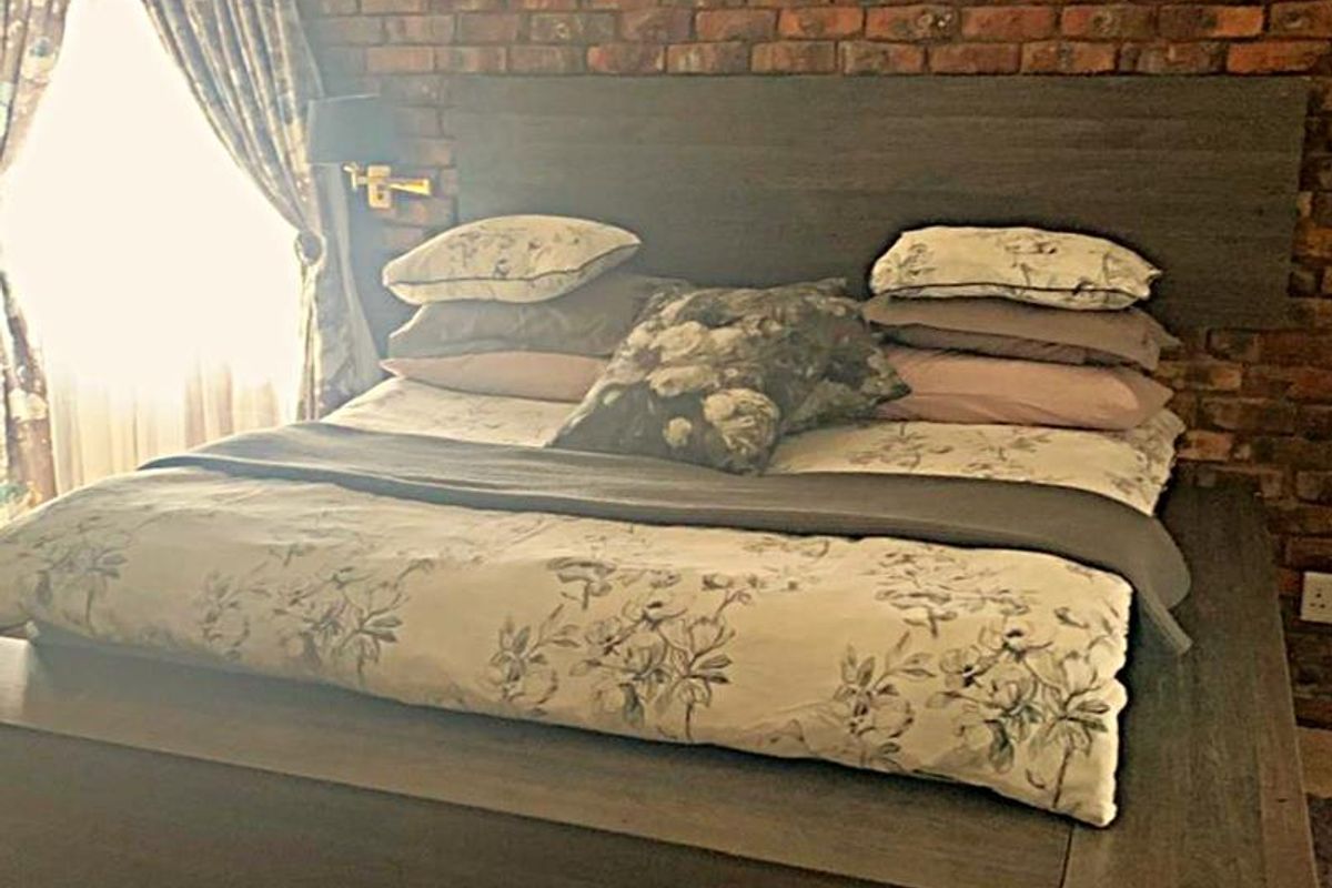 A bedroom featuring an exposed brick feature wall and tiled flooring, providing a rustic aesthetic.