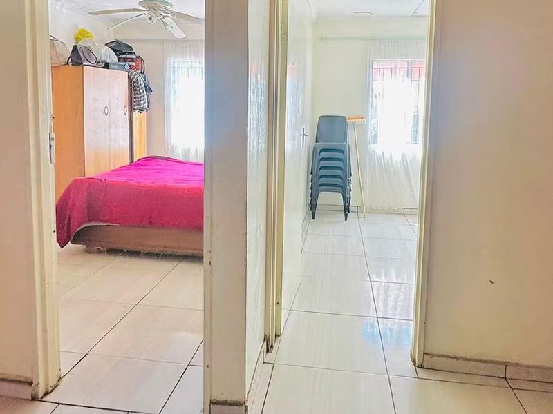 A view from a hallway looking into two adjacent bedrooms featuring tiled flooring and standard door frames.