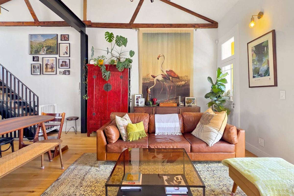 Spacious living area featuring exposed timber ceiling beams, a prominent steel structural beam, and warm hardwood flooring, creating an inviting open-plan atmosphere.