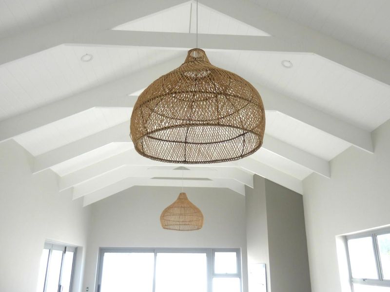 Spacious living area featuring a high vaulted ceiling with exposed rafters, recessed lighting, and large sliding glass doors providing ample natural light.