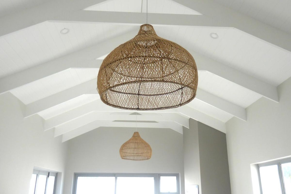 Spacious living area featuring a high vaulted ceiling with exposed rafters, recessed lighting, and large sliding glass doors providing ample natural light.
