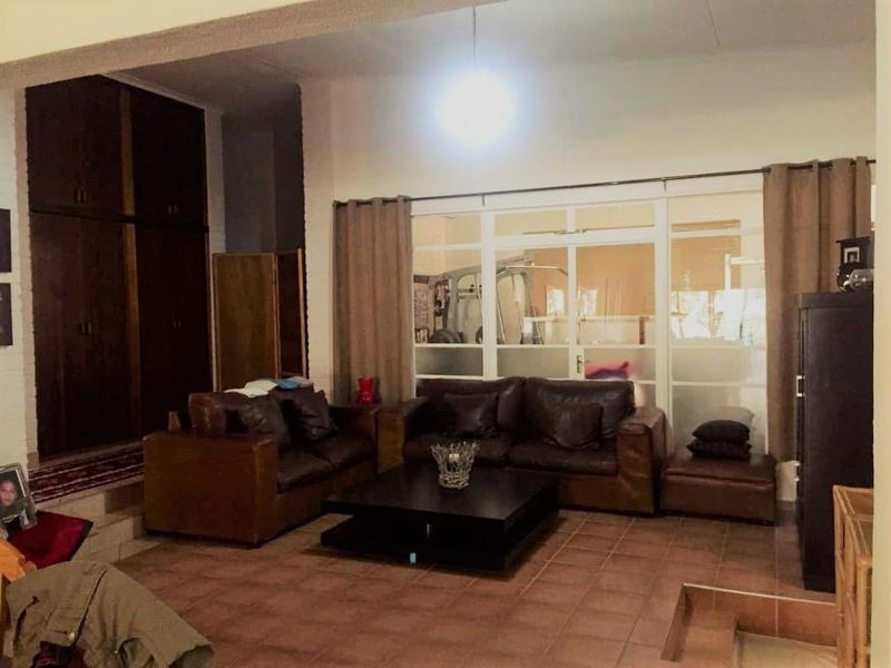 Spacious living area featuring terracotta floor tiles, built-in storage cabinetry, and large glass panel doors leading to an adjacent room.