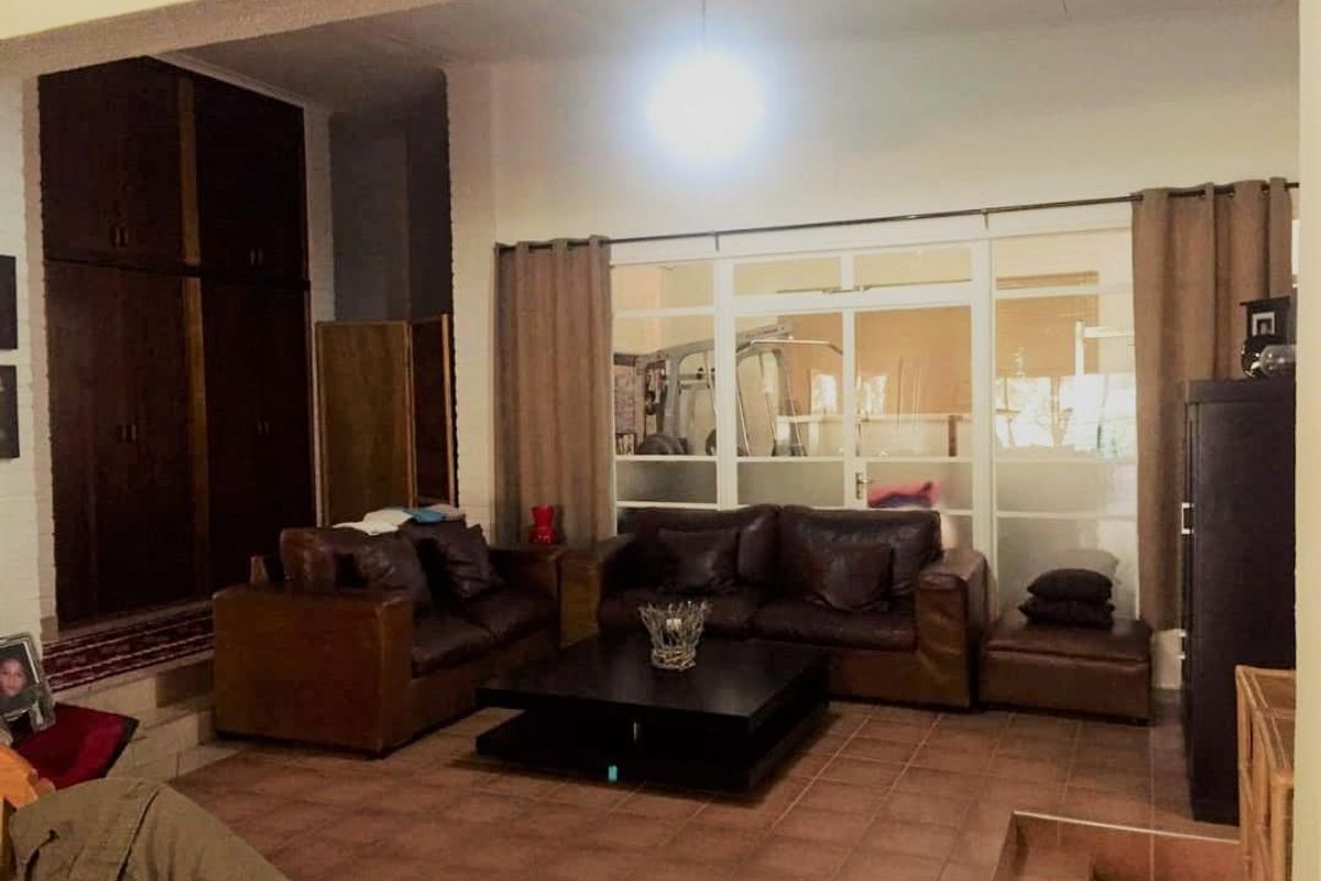 Spacious living area featuring terracotta floor tiles, built-in storage cabinetry, and large glass panel doors leading to an adjacent room.