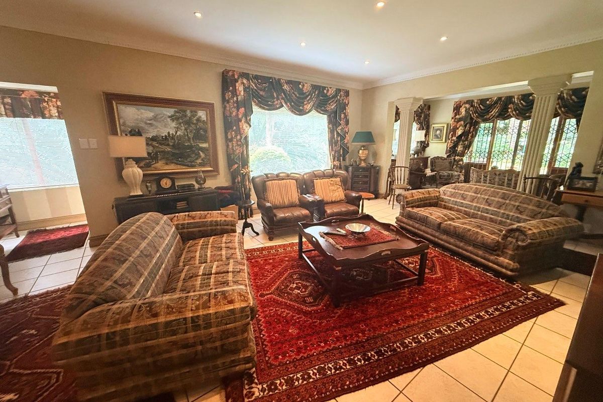 Spacious living room featuring tiled flooring, recessed downlighting, and decorative columns separating the seating area from the adjacent space.