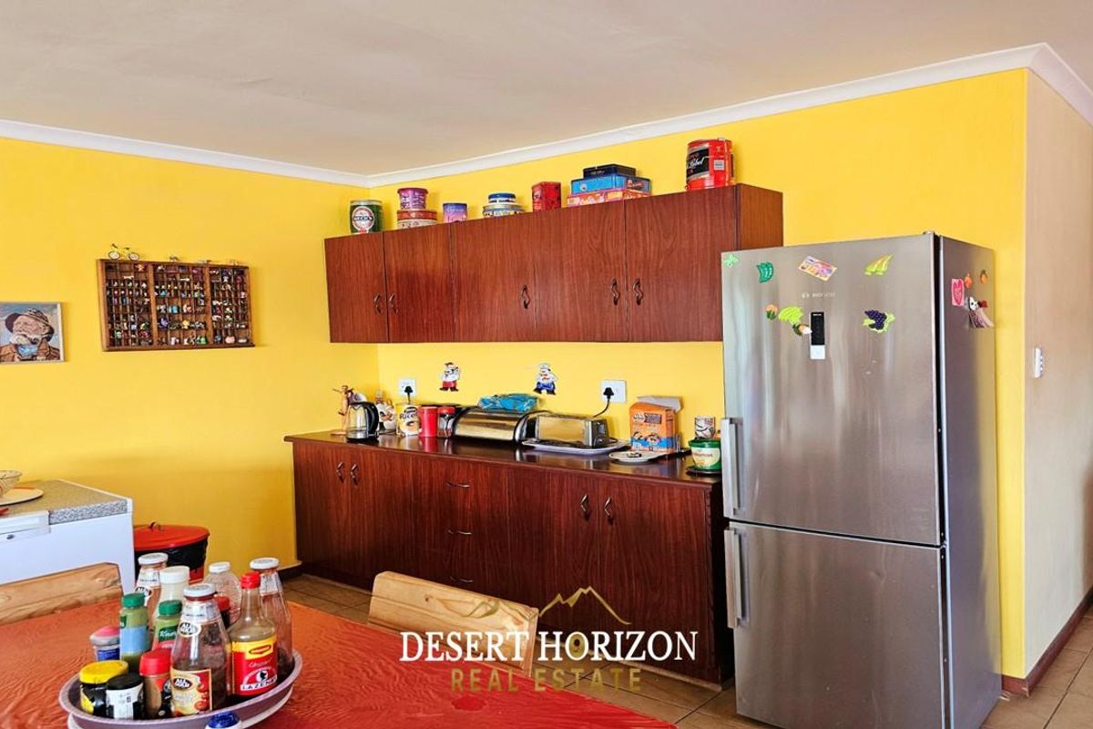 A functional kitchen area featuring dark wood-veneer cabinetry, tiled flooring, and bright yellow walls, providing a practical workspace for daily meal preparation.