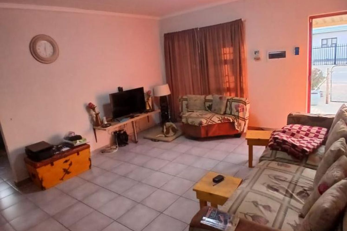 A living room featuring tiled flooring and a ceiling light fixture, with direct access to an exterior area.