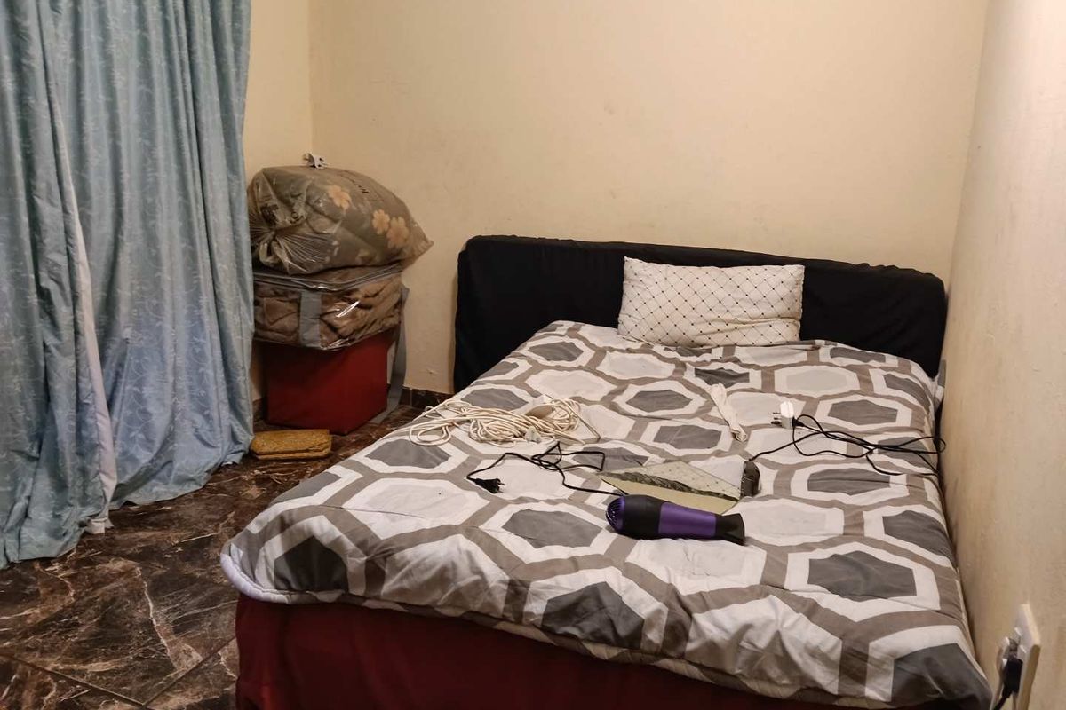 A bedroom featuring dark tiled flooring and plain walls, currently requiring cosmetic updates and maintenance to improve the overall aesthetic and condition.