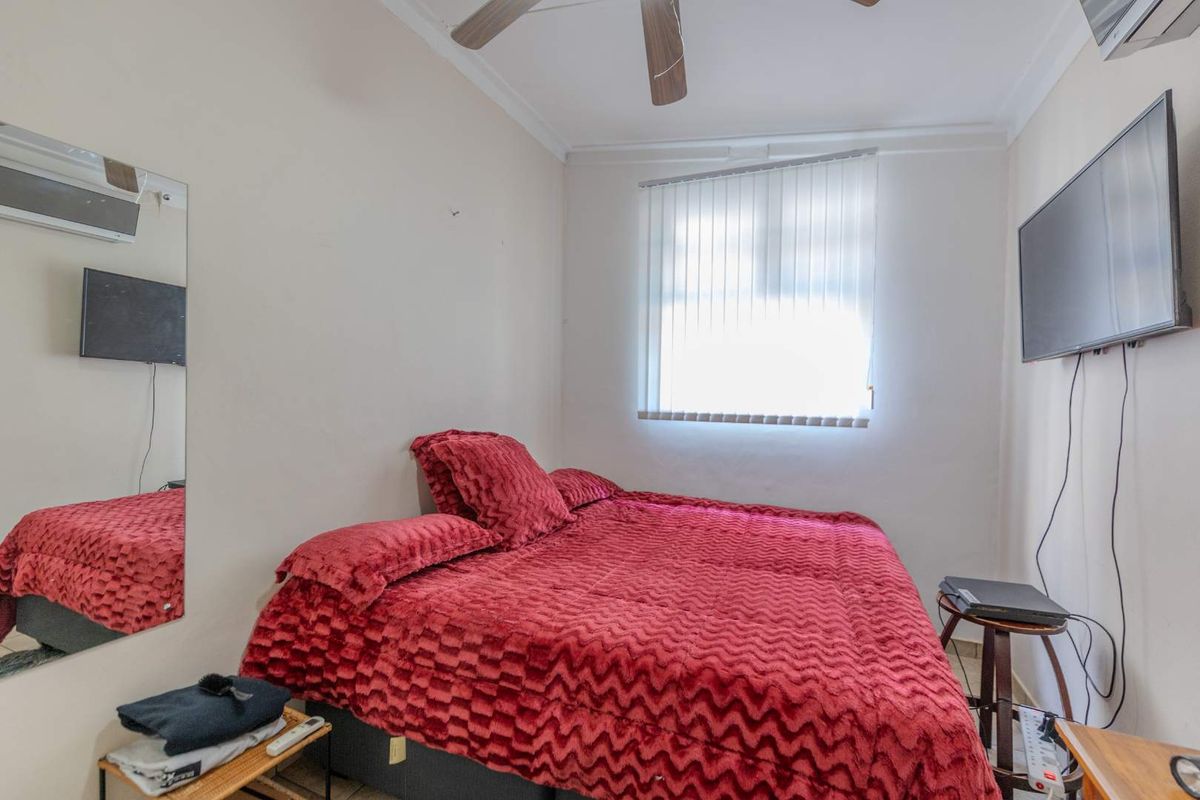 A compact bedroom featuring a ceiling fan, vertical blinds, and a wall-mounted air conditioning unit.