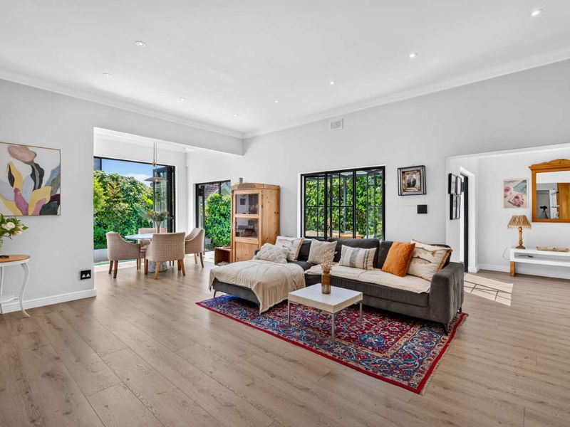 Spacious open-plan living and dining area featuring timber laminate flooring, recessed downlights, and large bi-fold doors opening to the garden.