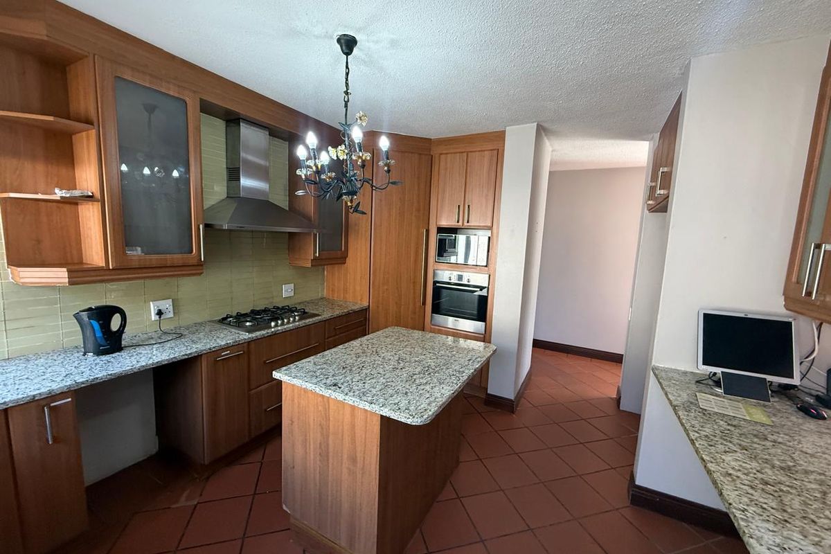 A functional kitchen featuring wooden cabinetry, granite countertops, a central island, and built-in appliances including an oven, microwave, and gas hob.