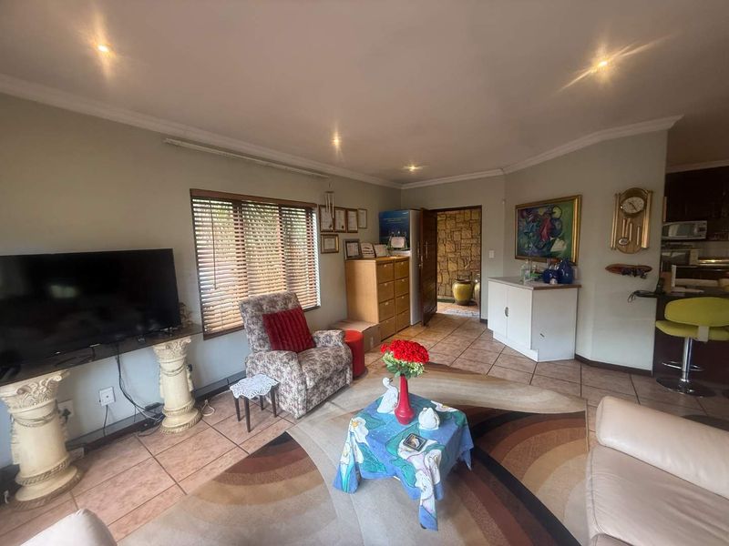 Open-plan living area featuring tiled flooring, recessed downlighting, and a stone-clad feature wall, providing a versatile space for relaxation and dining.