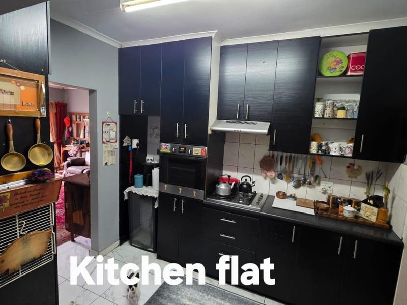A functional kitchen featuring dark cabinetry, a built-in oven, gas hob, extractor fan, and tiled flooring, providing a practical workspace for daily cooking.