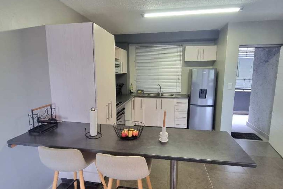 A functional kitchen featuring a breakfast bar, built-in cabinetry, stainless steel sink, and tiled flooring, providing a practical layout for daily meal preparation.