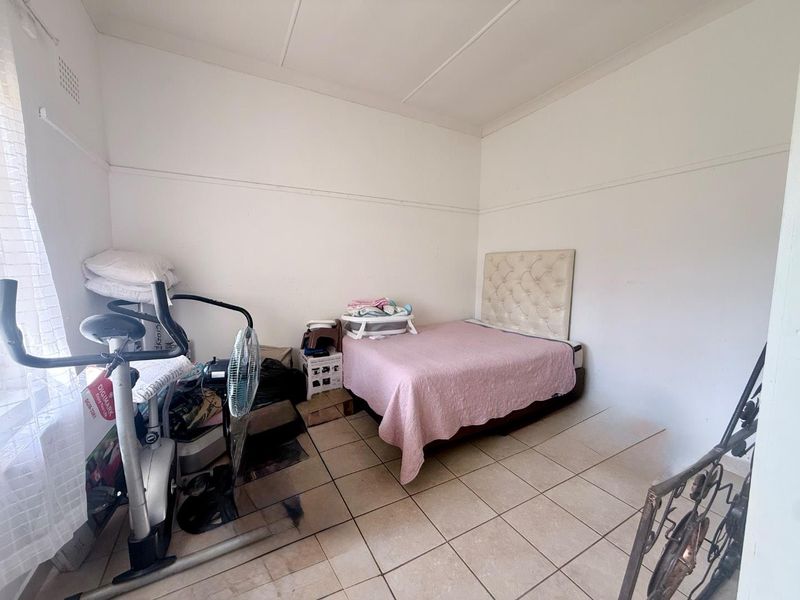 A bedroom featuring tiled flooring and coved ceilings, currently used as a multi-purpose space.