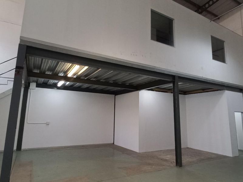 Industrial warehouse space featuring a mezzanine level, steel staircase, and open-plan ground floor area suitable for storage or workshop operations.