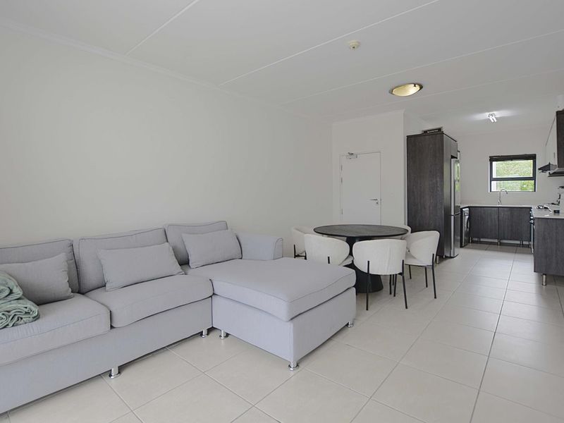 Open-plan living and dining area featuring tiled floors and a modern kitchen with built-in cabinetry and integrated appliances.