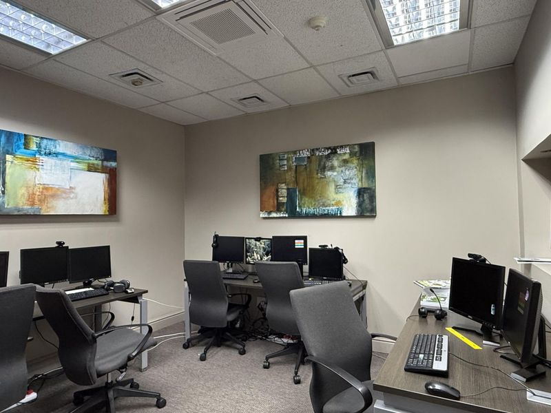 A functional office space featuring a suspended ceiling with recessed lighting, air conditioning vents, and carpeted flooring.