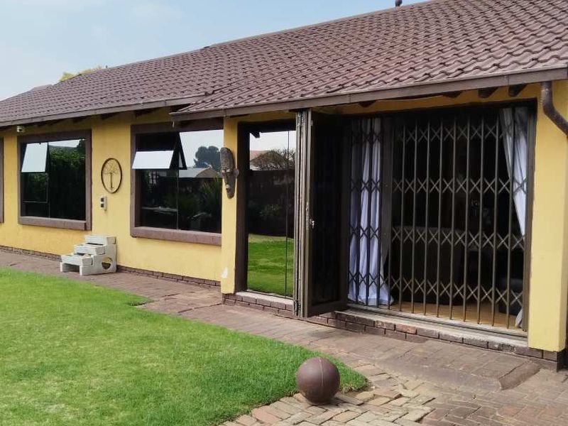 Rear exterior view of the house featuring a tiled roof, brick paved patio area, and secure sliding door access.