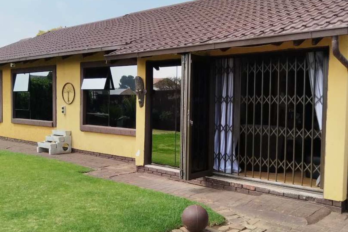 Rear exterior view of the house featuring a tiled roof, brick paved patio area, and secure sliding door access.
