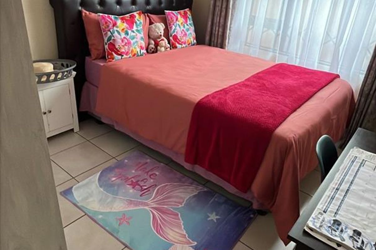 A functional bedroom featuring tiled flooring and a window with curtain treatments, providing a comfortable and practical living space.
