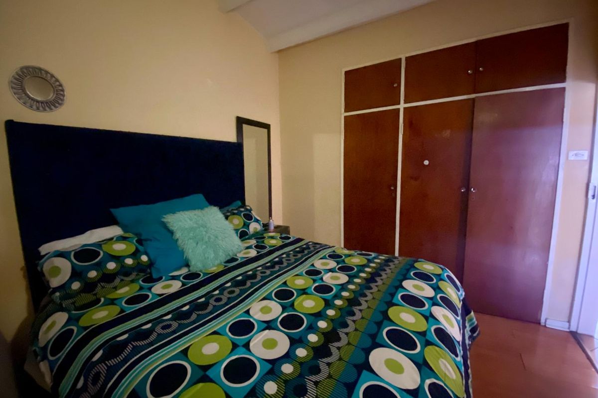 A bedroom featuring built-in wooden cupboards with overhead storage compartments and laminate flooring.