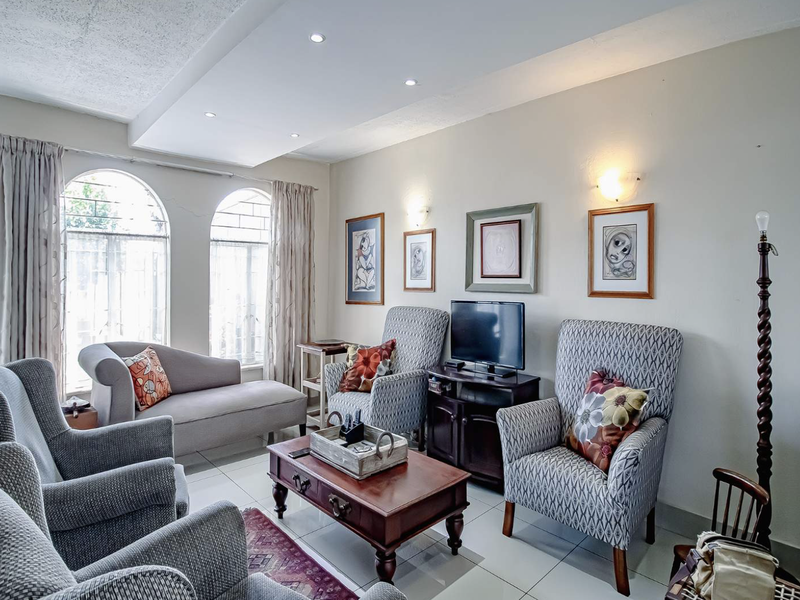 A comfortable living room featuring arched windows, recessed ceiling lighting, and tiled flooring, providing a bright and functional space.