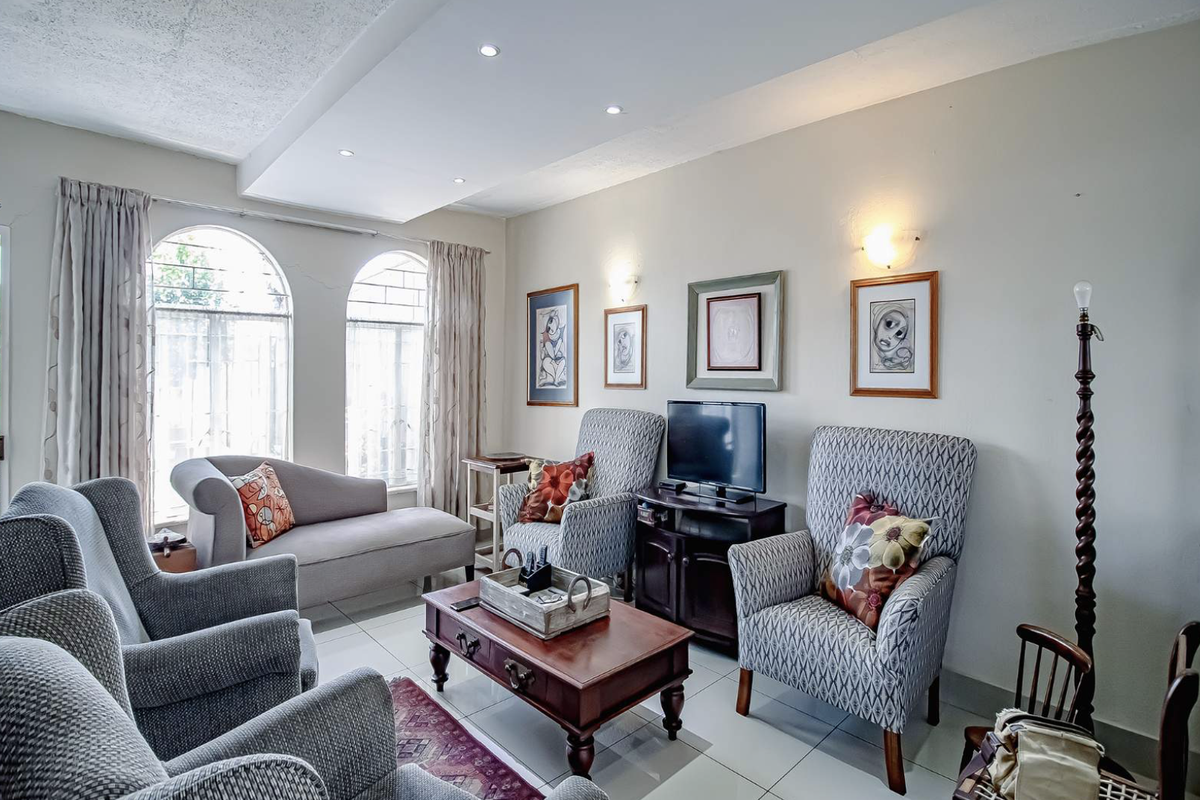 A comfortable living room featuring arched windows, recessed ceiling lighting, and tiled flooring, providing a bright and functional space.