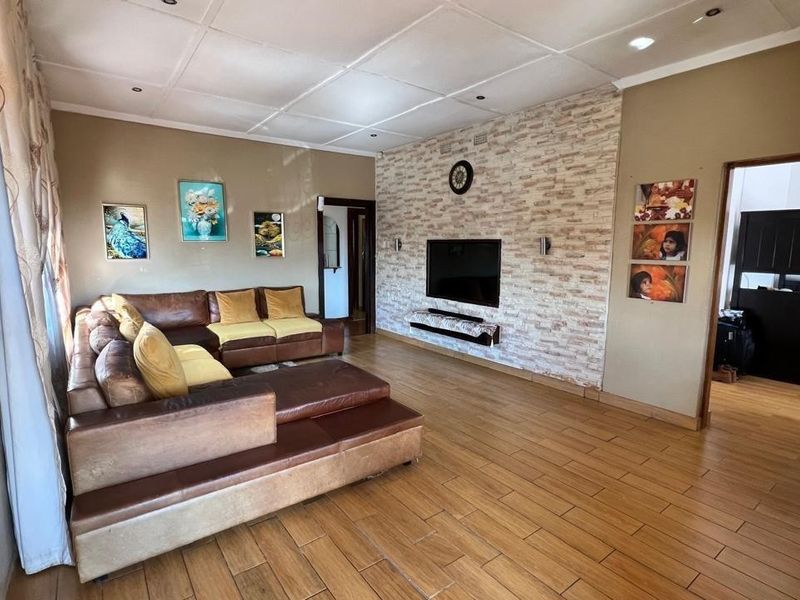 Spacious living room featuring wood-look tiled flooring, a textured stone-effect feature wall, and recessed ceiling lighting.