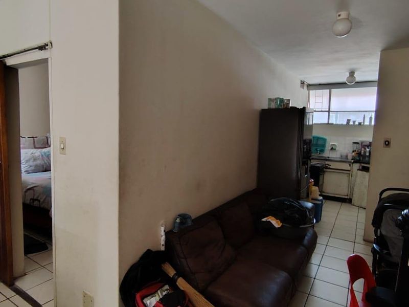 Open plan living area featuring tiled flooring and a compact kitchen space with built-in cabinetry and sink.