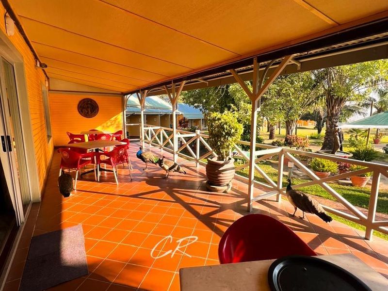 A covered outdoor patio area featuring tiled flooring and a timber balustrade, overlooking the hotel grounds.