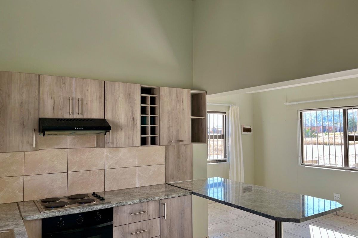 Modern kitchen featuring wood-look cabinetry, granite countertops, a built-in oven and hob, and a breakfast bar, set within an open-plan living space.