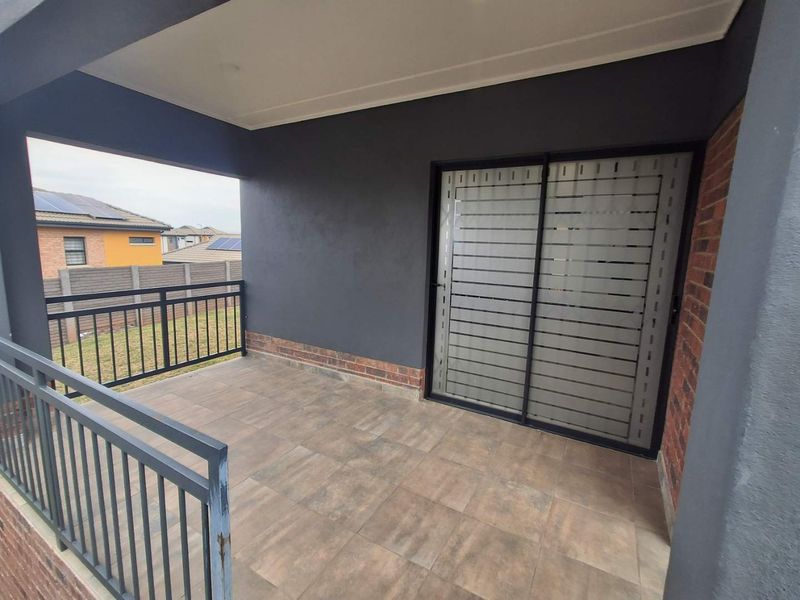 A covered balcony featuring tiled flooring, a metal safety balustrade, and a sliding glass door with privacy frosting.