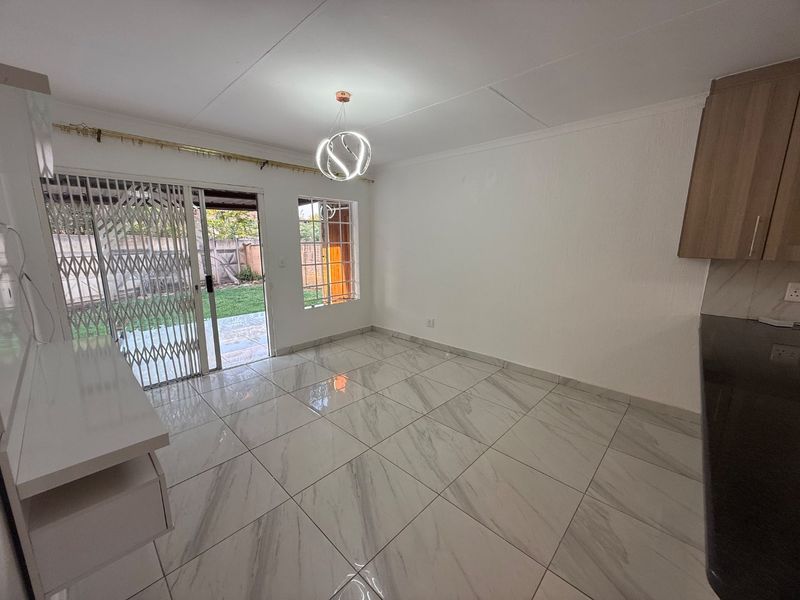 Bright open-plan living area featuring modern marble-look floor tiles, built-in cabinetry, and direct access to the rear garden through a sliding glass door.