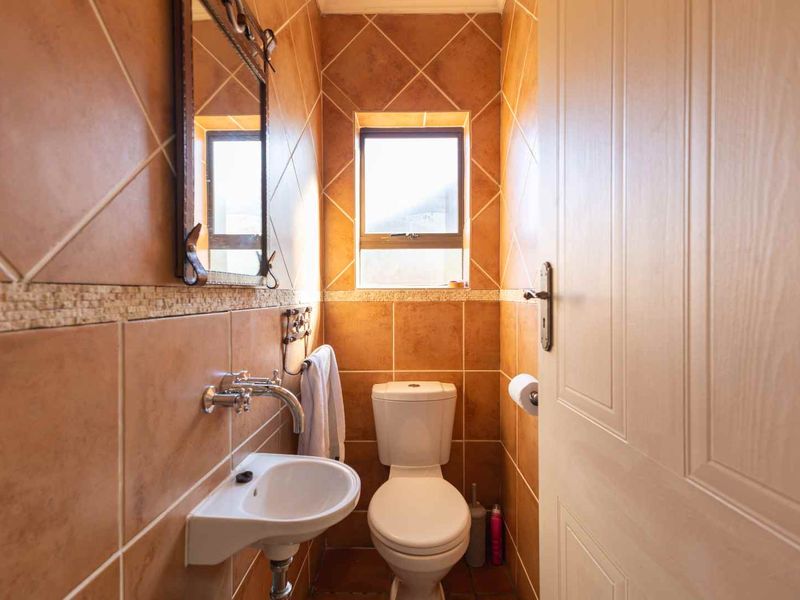 A compact guest bathroom featuring tiled walls, a wall-mounted basin, and a standard toilet.