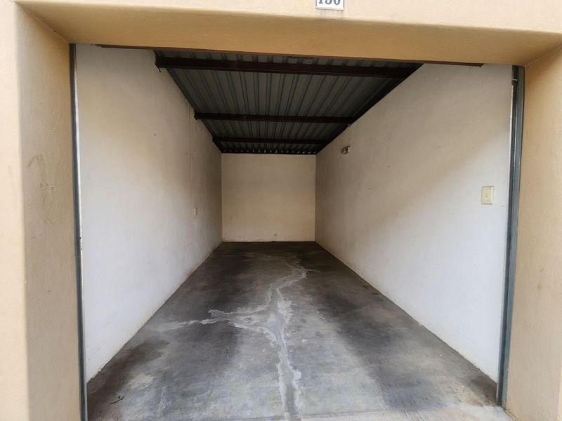 A clean, empty single-car garage featuring a concrete floor, exposed metal roof structure, and basic electrical fixtures.