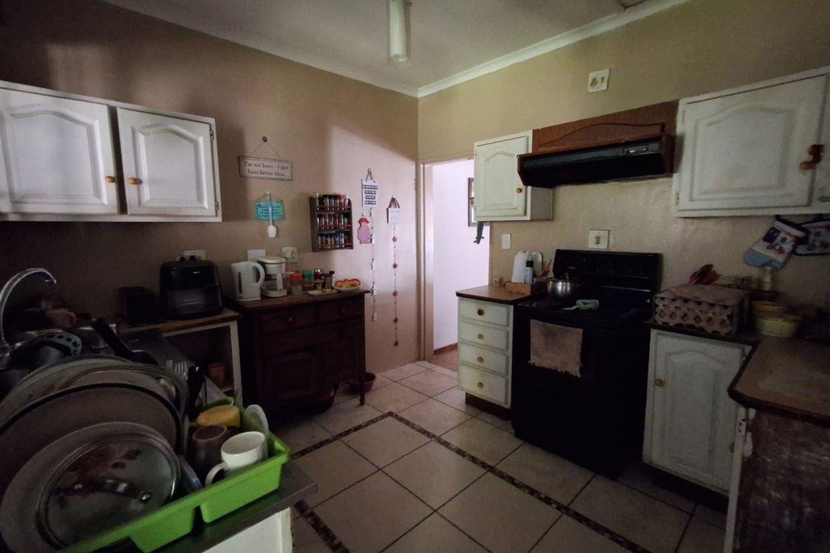 A functional kitchen featuring built-in cabinetry, a stove with an extractor fan, and tiled flooring, offering potential for modernization and aesthetic updates.