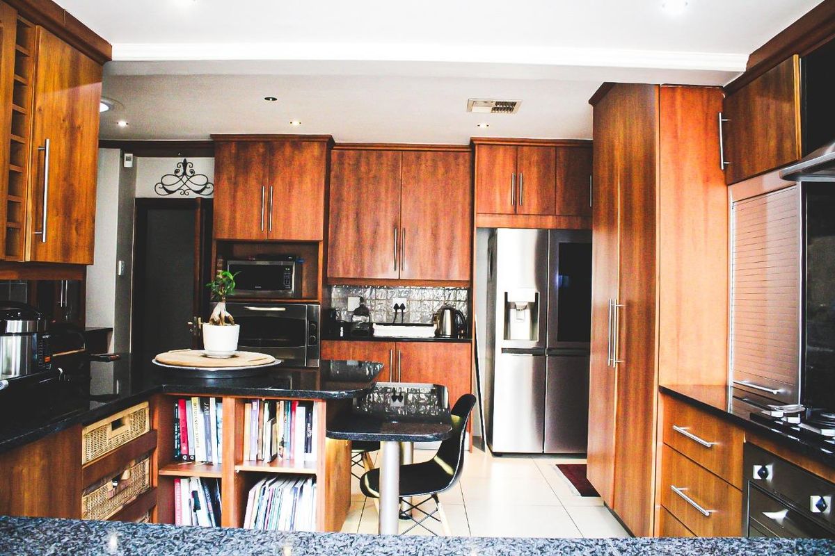 A well-appointed kitchen featuring warm wood-toned cabinetry, dark granite countertops, and integrated stainless steel appliances, offering a functional and classic culinary space.