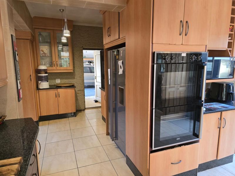 A functional kitchen featuring wood-finish cabinetry, granite countertops, and a built-in double oven, with tiled flooring and direct access to an exterior area.