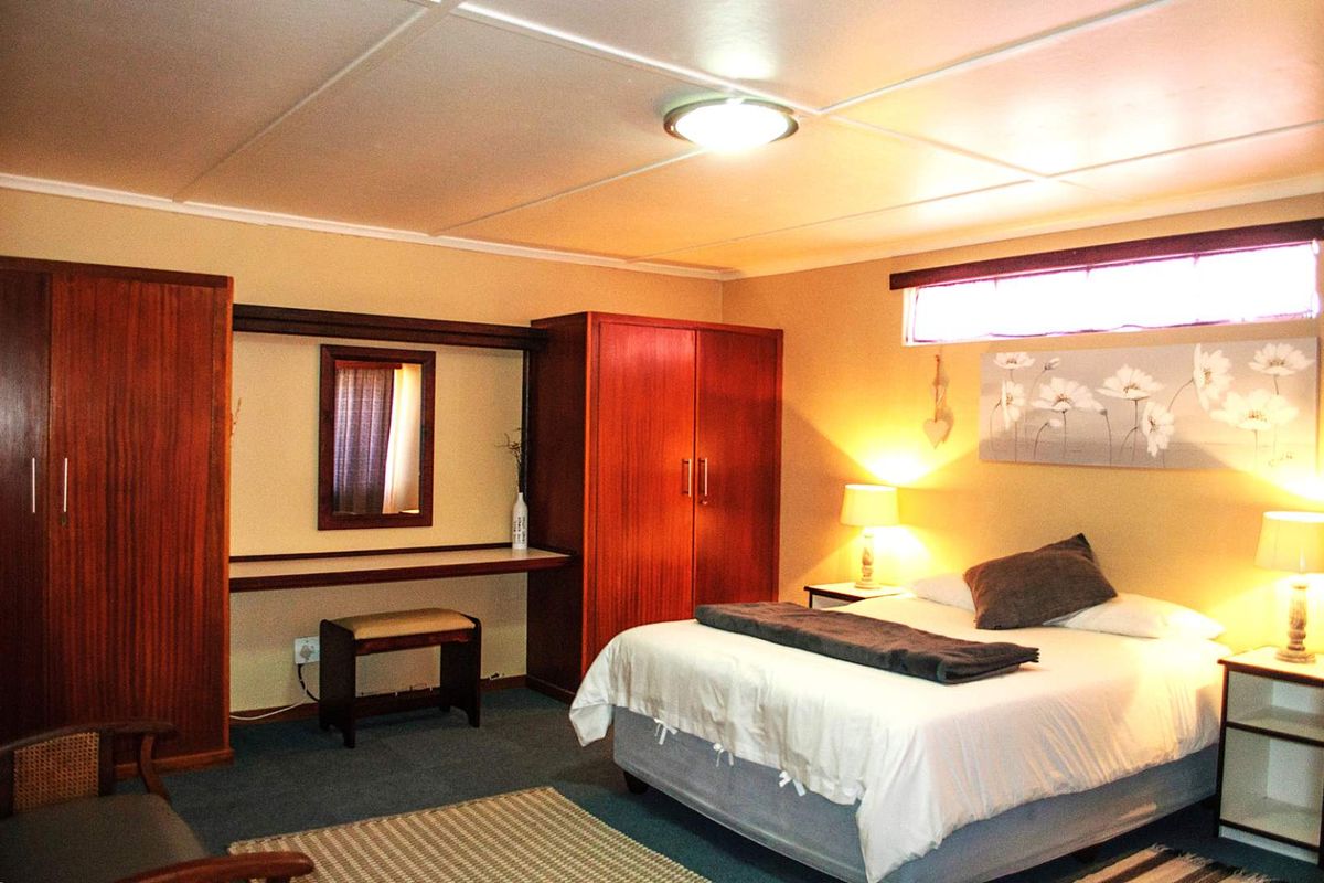 A bedroom featuring built-in wooden cabinetry, a vanity area, and a high-level window, providing a functional and comfortable sleeping space.