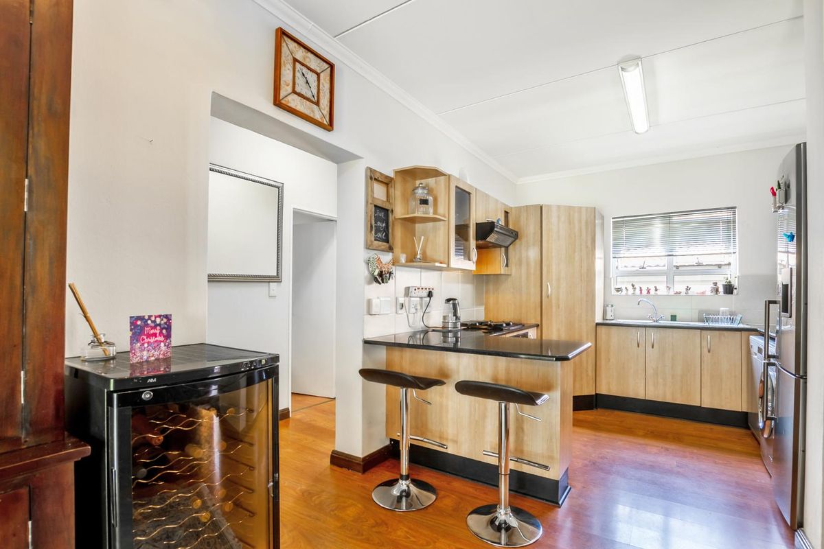 A functional kitchen featuring light wood-finish cabinetry, dark granite countertops, a breakfast bar, and integrated cooking appliances with laminate flooring throughout.