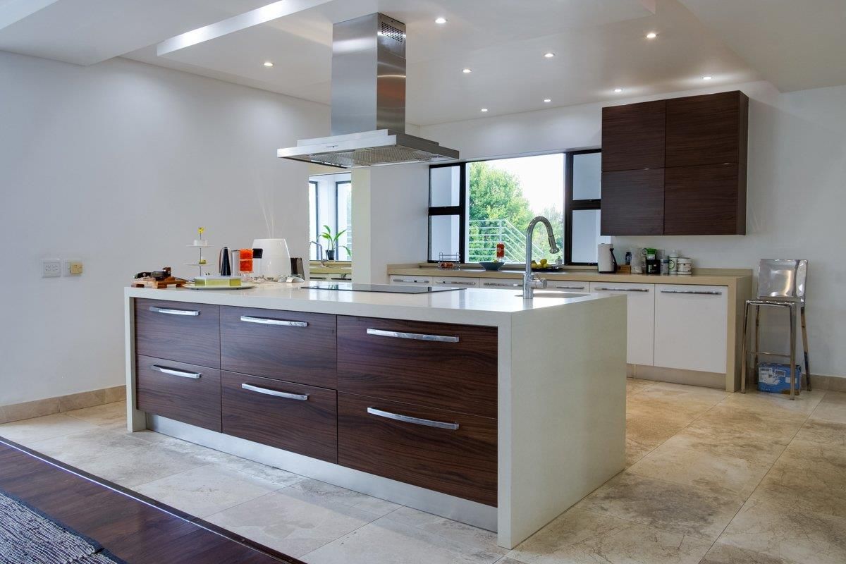 Modern kitchen featuring a large central island with stone countertop, integrated hob, stainless steel extractor fan, and contemporary two-tone cabinetry.