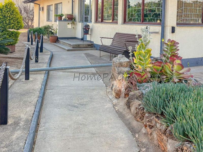 Front exterior view of the property featuring a concrete walkway, stone retaining wall, and security bars on the windows.