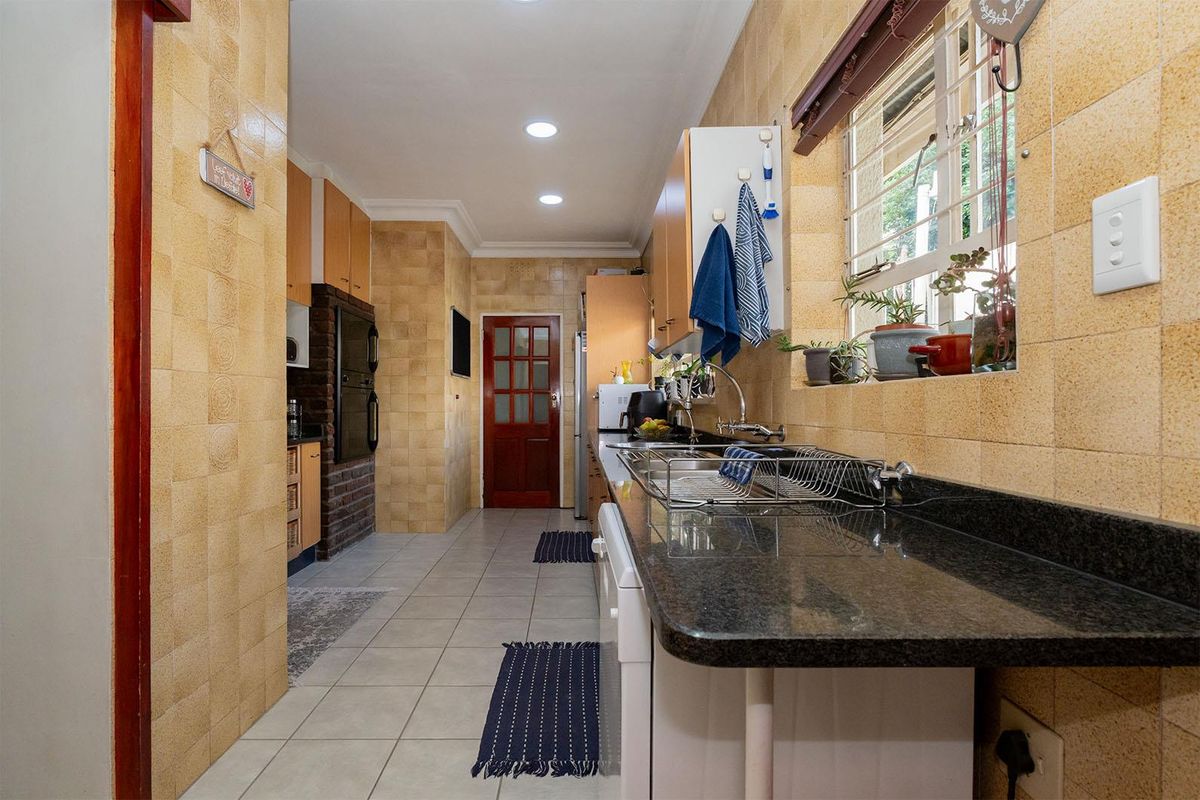 A functional kitchen featuring granite countertops, built-in cabinetry, tiled walls, and recessed ceiling lighting.